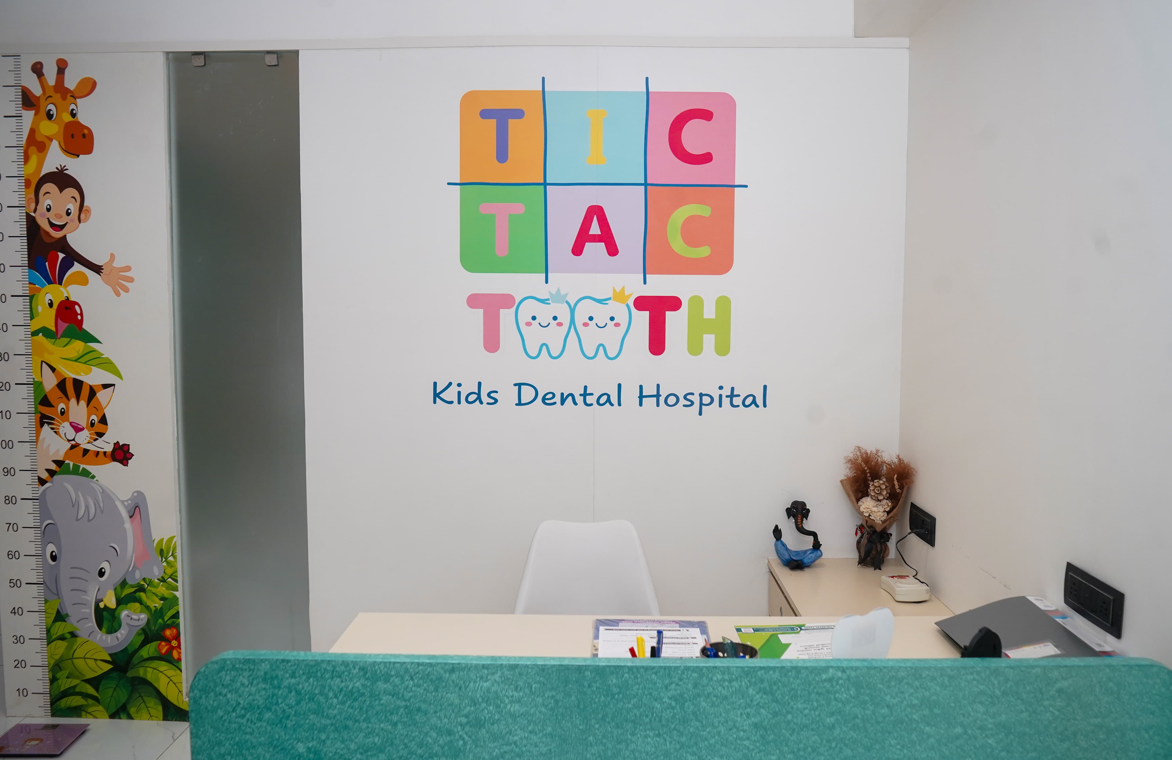 The reception desk, with a teal front and the Tic Tac Tooth logo on the wall behind it