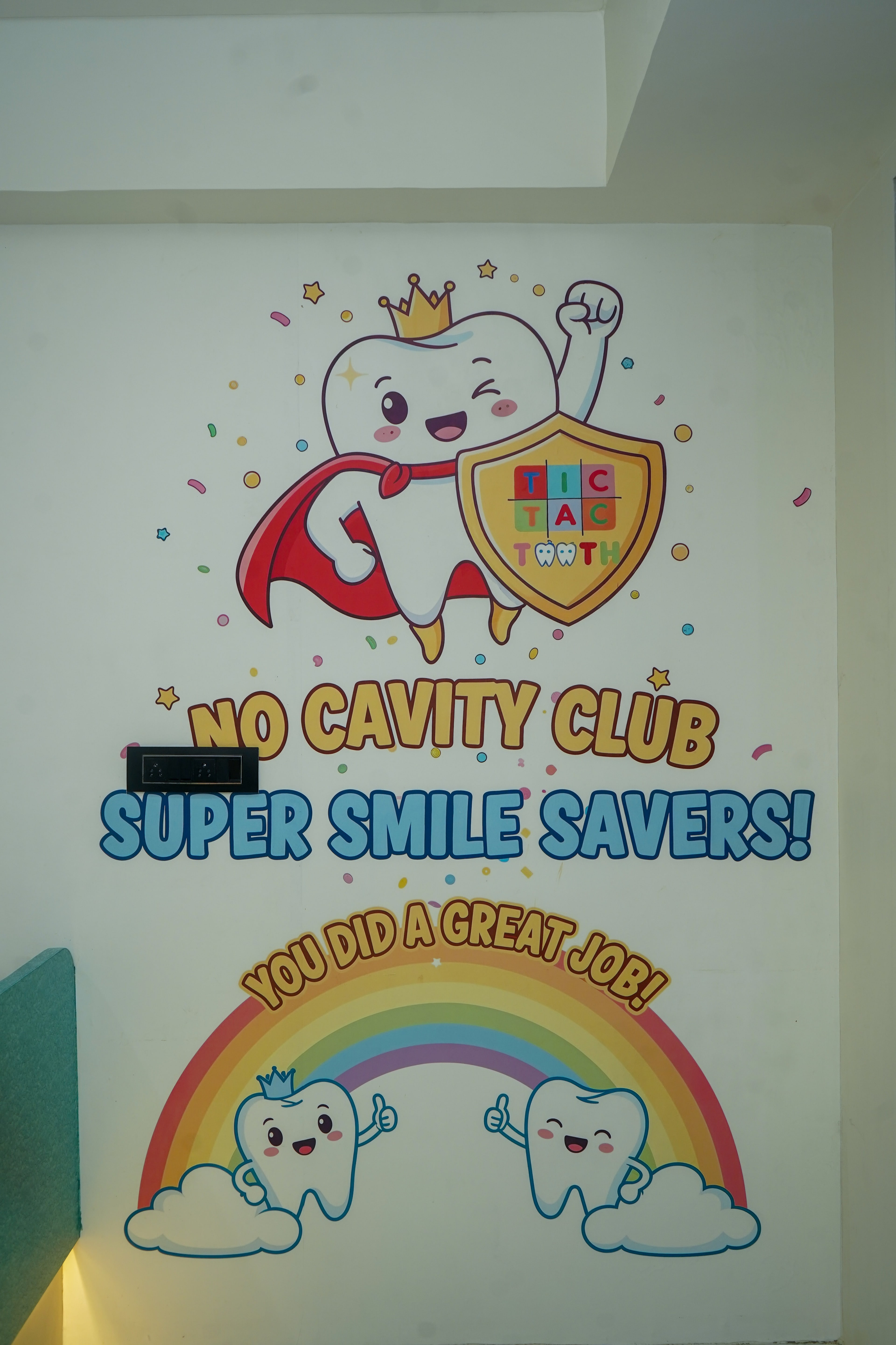 The No Cavity Club mural: the superhero-tooth mascot with a gold shield, and two tooth characters giving thumbs up beneath a rainbow reading 'You did a great job!'
