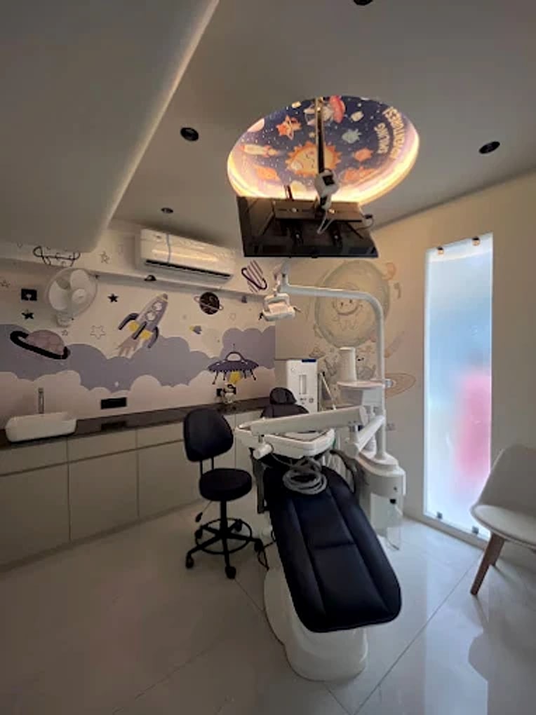 The space room's backlit circular ceiling mural, lit warm gold above the navy chair, with the cloud and rocket mural on the wall and a frosted glass door